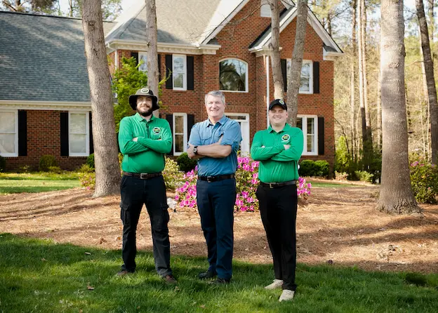 Team of three Mosquito Joe Service Professionals standing in front of a home with their arms crossed.