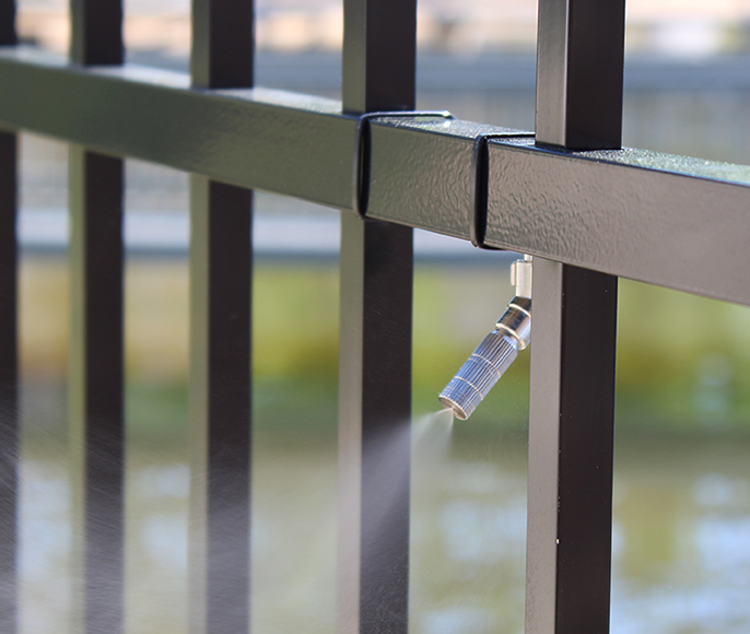 Barrier spray system on black metal gate.